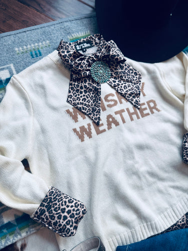 White sweater with leopard print accents and 'Whiskey Weather' text on a textured surface.