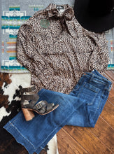 Load image into Gallery viewer, Leopard print top, bow tie collar, blue jeans, and brown heeled boots on a wooden floor with a colorful rug.
